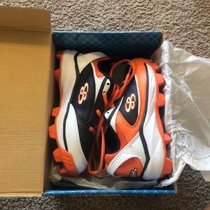 Black, white, and orange baseball cleats